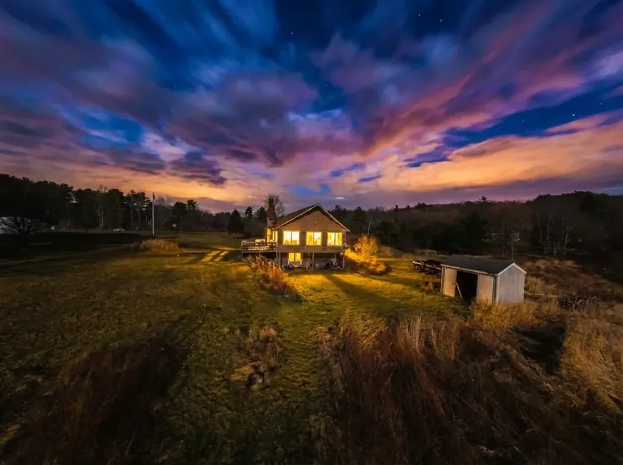 Farmhouse at dusk under a dramatic sky